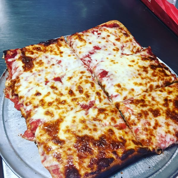 A square-cut Mike's Pizzeria cheese pizza with a golden-brown crust on a metal tray.