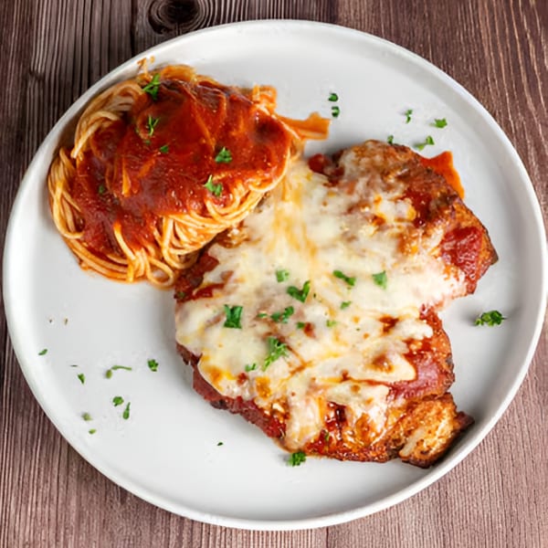 Chicken Parmesan with melted mozzarella cheese and spaghetti with red sauce, garnished with parsley.